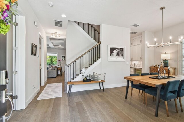 3607 W Roland St, Tampa, FL 33609 - dining area featuring stairway, visible vents, light wood-style floors, baseboards, and a notable chandelier