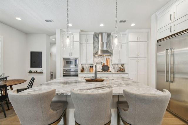 3607 W Roland St, Tampa, FL 33609 - kitchen with recessed lighting, decorative backsplash, built in appliances, white cabinets, and wall chimney exhaust hood