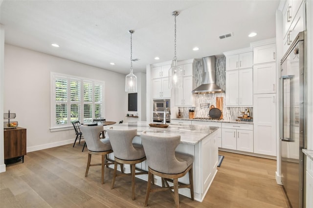 3607 W Roland St, Tampa, FL 33609 - kitchen with wall chimney range hood, white cabinets, built in appliances, visible vents, and backsplash