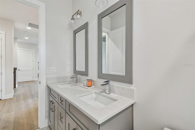 3607 W Roland St, Tampa, FL 33609 - bathroom featuring double vanity, wood finished floors, visible vents, and a sink