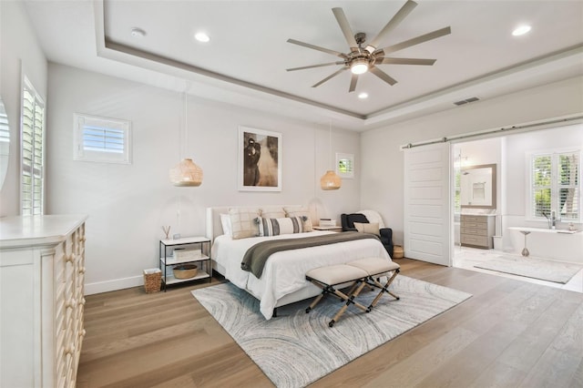 3607 W Roland St, Tampa, FL 33609 - bedroom featuring a barn door, visible vents, a raised ceiling, and light wood-style floors