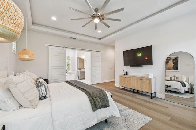 3607 W Roland St, Tampa, FL 33609 - bedroom featuring a raised ceiling, a barn door, light wood-type flooring, and baseboards