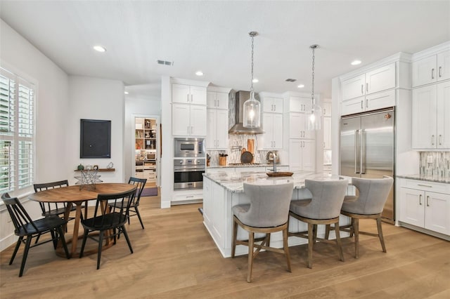 3607 W Roland St, Tampa, FL 33609 - kitchen with white cabinets, backsplash, wall chimney range hood, and built in appliances