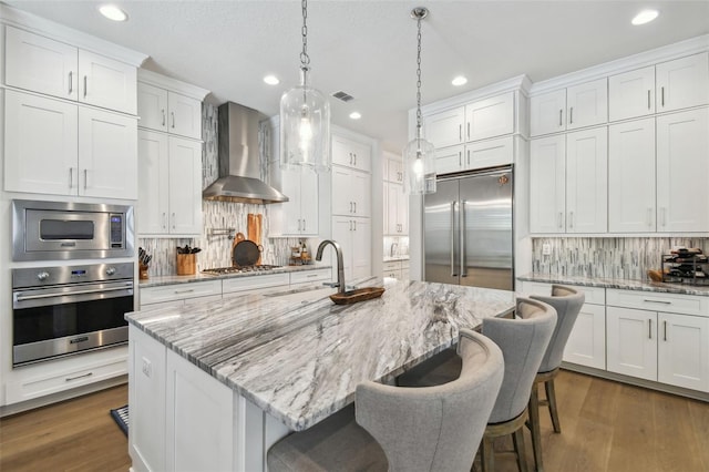 3607 W Roland St, Tampa, FL 33609 - kitchen featuring wall chimney range hood, decorative backsplash, a sink, built in appliances, and recessed lighting