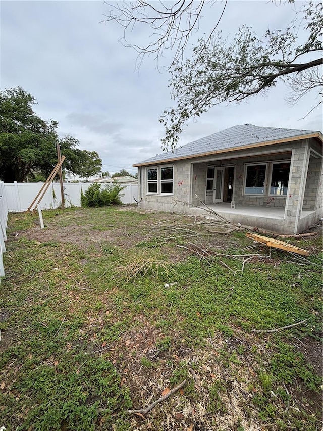 back of property featuring a fenced backyard, a patio, and concrete block siding
