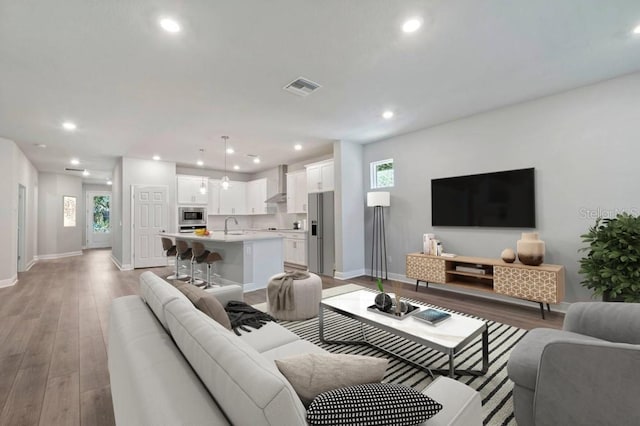 living area featuring recessed lighting, visible vents, and baseboards