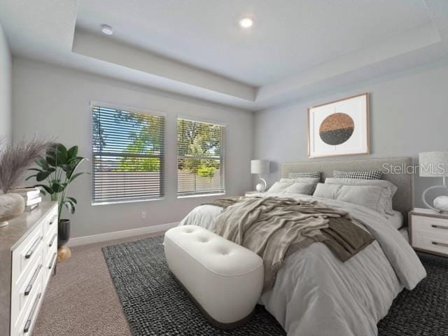 carpeted bedroom with a tray ceiling and baseboards