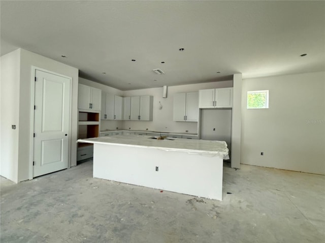 1828 27th Ave N, Saint Petersburg, FL 33713 - kitchen featuring a kitchen island, white cabinets, concrete flooring, and light countertops