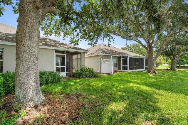 19232 Barred Owl Ct, Land O Lakes, FL 34638 - rear view of house featuring a sunroom, stucco siding, a lawn, and a shingled roof