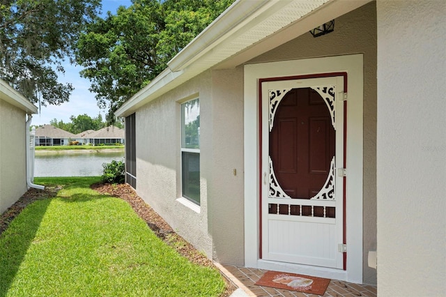 19232 Barred Owl Ct, Land O Lakes, FL 34638 - doorway to property with stucco siding, a water view, and a lawn