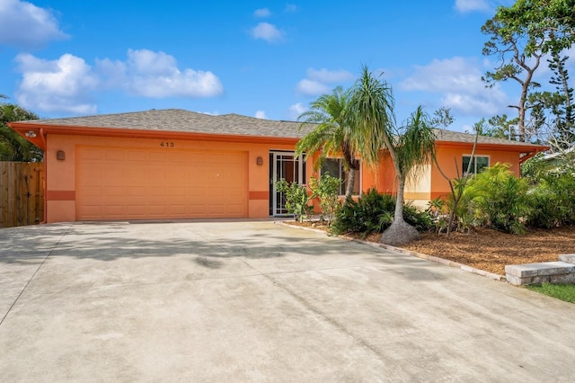view of front of house featuring an attached garage, fence, driveway, and stucco siding