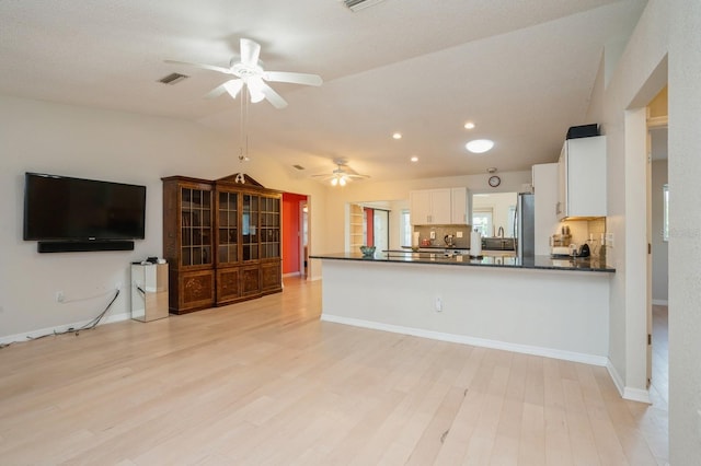 kitchen featuring visible vents, white cabinets, dark countertops, freestanding refrigerator, and a ceiling fan