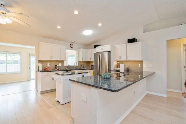 kitchen with a peninsula, freestanding refrigerator, vaulted ceiling, and light wood-style floors