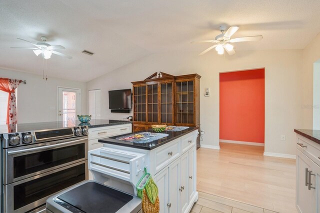 kitchen with visible vents, ceiling fan, white cabinetry, and double oven range