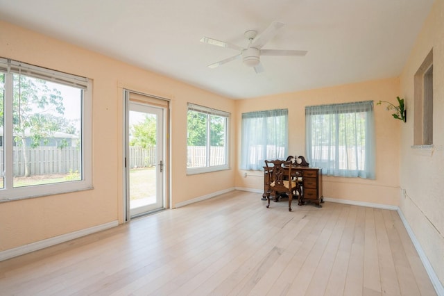 interior space featuring baseboards, wood finished floors, and a healthy amount of sunlight