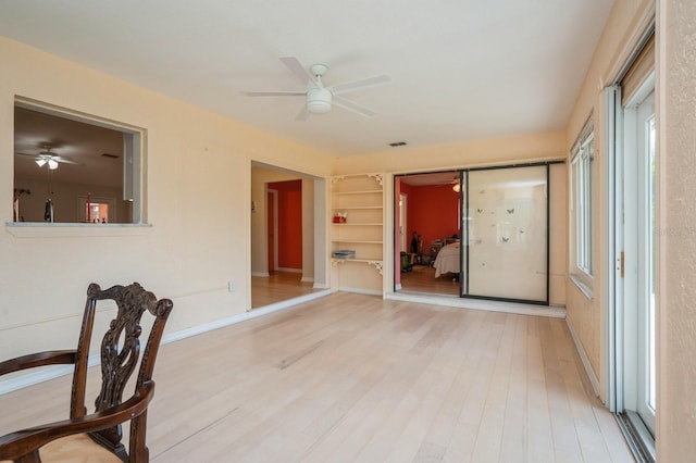 interior space featuring light wood-type flooring, baseboards, a ceiling fan, and visible vents