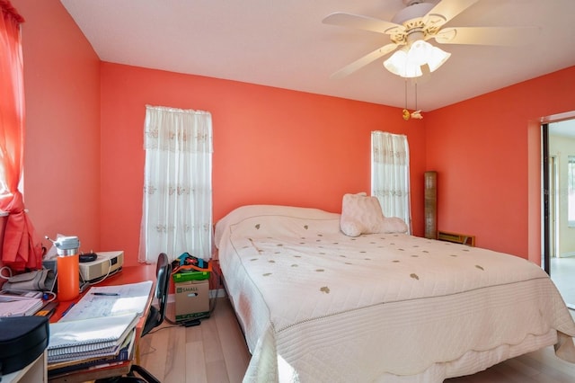 bedroom with ceiling fan, multiple windows, and wood finished floors