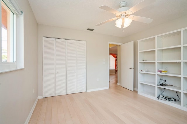 unfurnished bedroom with ceiling fan, a closet, visible vents, light wood finished floors, and baseboards