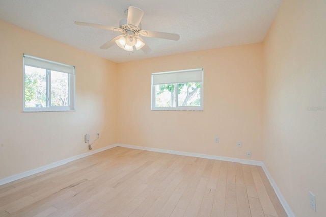empty room with light wood finished floors, baseboards, and ceiling fan