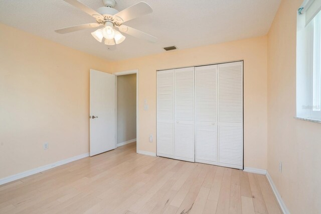 unfurnished bedroom with a closet, light wood finished floors, baseboards, and visible vents