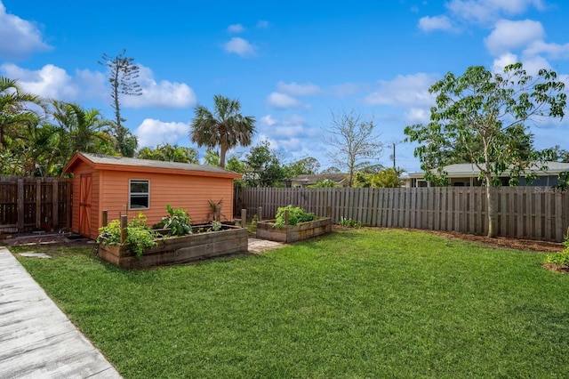 view of yard with a garden, a fenced backyard, an outdoor structure, and a storage unit