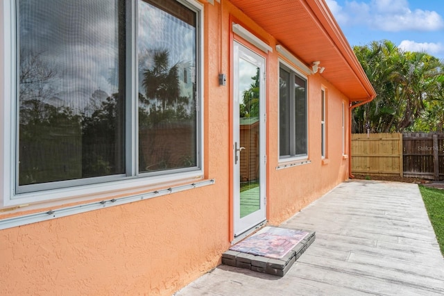 exterior space with fence, a wooden deck, and stucco siding