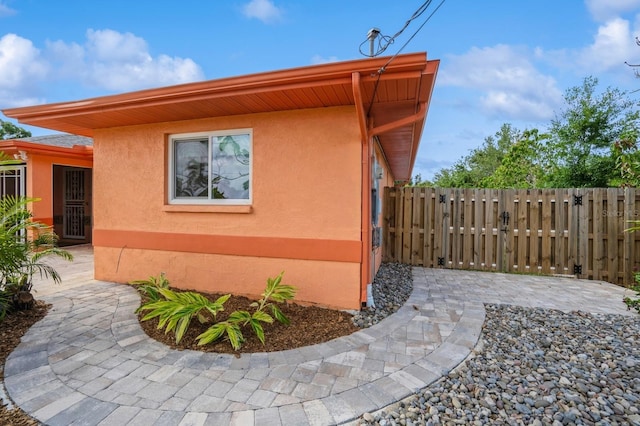 view of property exterior featuring a patio area, stucco siding, and fence