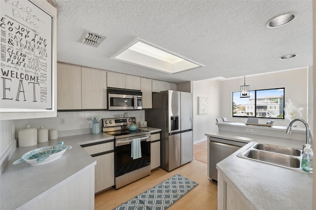 2387 Hanover Dr Unit 2387, Dunedin, FL 34698 - kitchen featuring stainless steel appliances, a sink, a textured ceiling, light wood finished floors, and tasteful backsplash