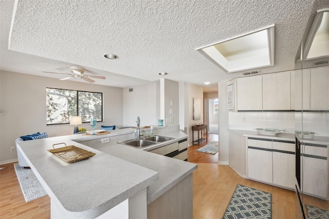 2387 Hanover Dr Unit 2387, Dunedin, FL 34698 - kitchen featuring a sink, a textured ceiling, light countertops, a peninsula, and light wood-style floors