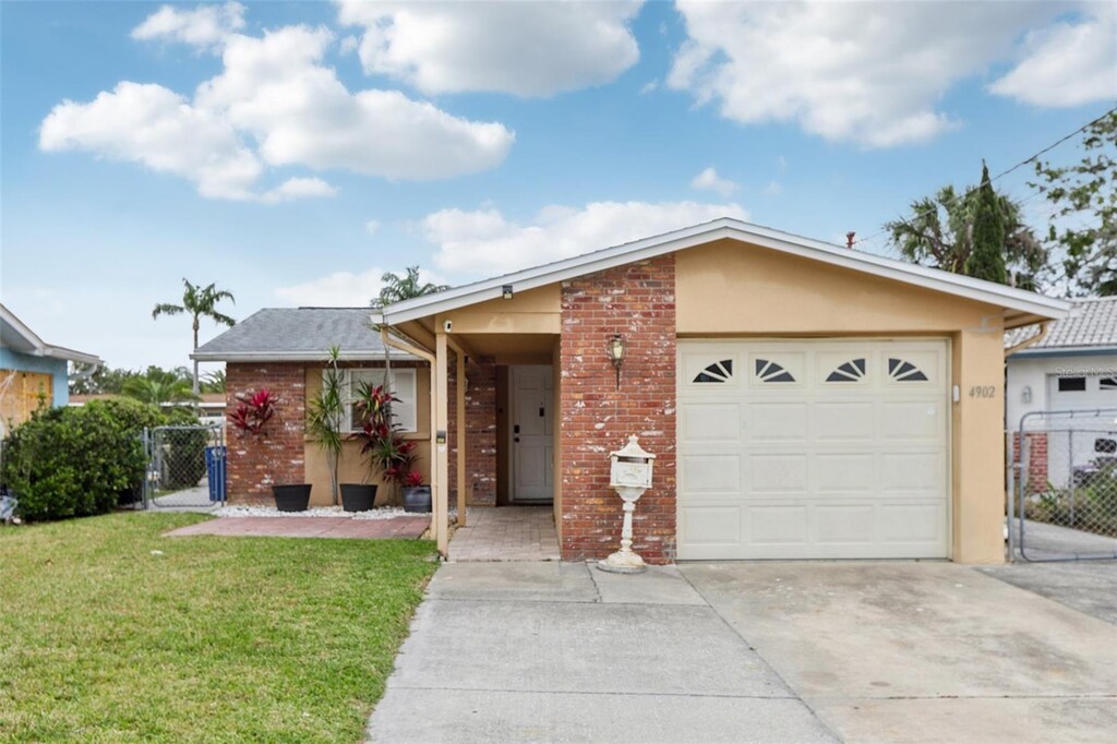 4902 Blue Heron Dr, New Port Richey, FL 34652 - ranch-style house with a garage, fence, a front lawn, a gate, and driveway