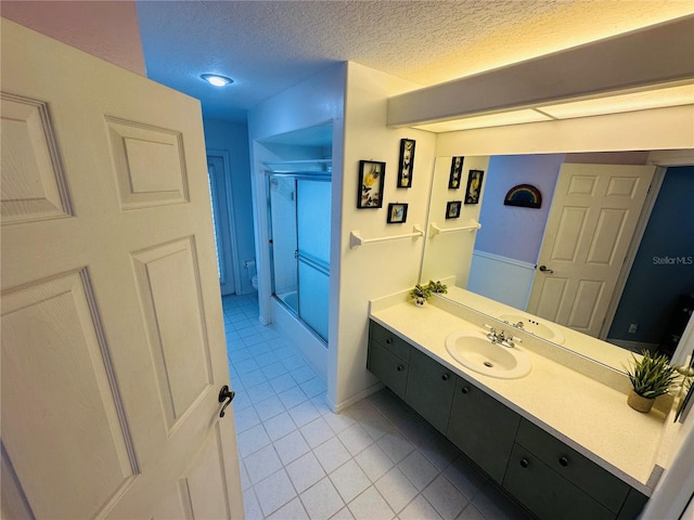 14334 Teasdale Ave, Hudson, FL 34667 - full bathroom with tile patterned floors, vanity, a textured ceiling, combined bath / shower with glass door, and toilet