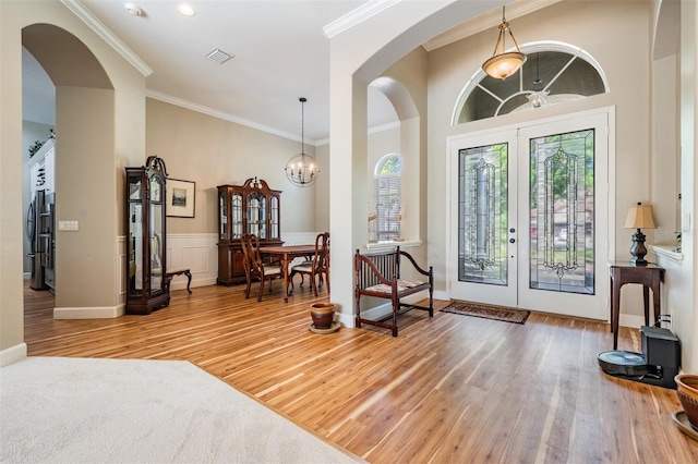 entryway featuring crown molding, visible vents, a chandelier, wood finished floors, and french doors