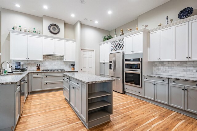 kitchen with gray cabinets, a sink, open shelves, and stainless steel appliances