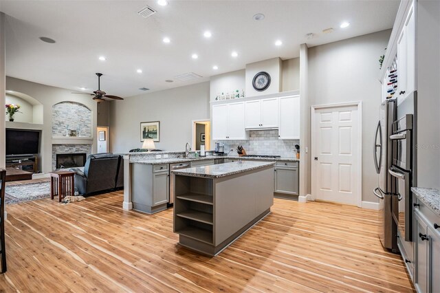kitchen featuring visible vents, a center island, a sink, a ceiling fan, and a fireplace