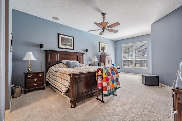 carpeted bedroom with a textured ceiling, ceiling fan, and baseboards