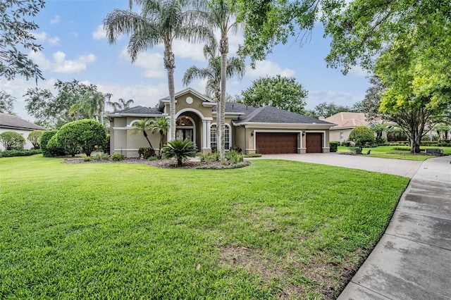 mediterranean / spanish house with concrete driveway, a front yard, stucco siding, and an attached garage