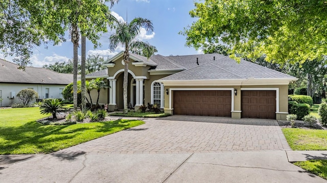 view of front of home featuring a garage, stucco siding, a front lawn, driveway, and roof with shingles