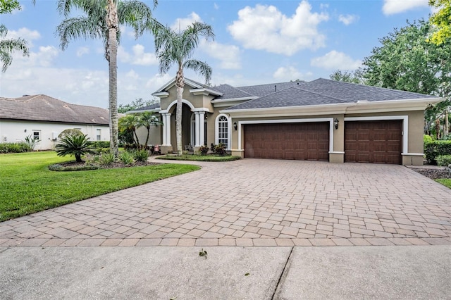 view of front of house featuring a front lawn, a garage, decorative driveway, and stucco siding