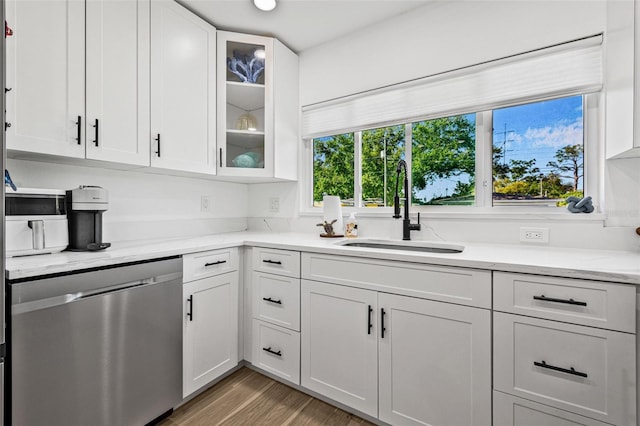 kitchen featuring stainless steel dishwasher, white cabinets, and a sink
