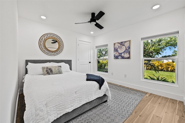 bedroom with wood finished floors, baseboards, multiple windows, and recessed lighting
