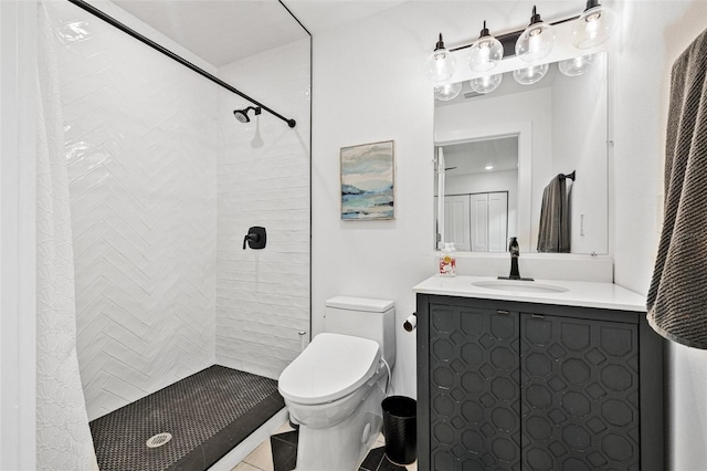 full bathroom featuring tile patterned flooring, vanity, a tile shower, and toilet