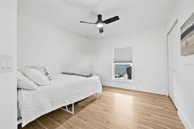 bedroom with wood finished floors, a closet, baseboards, and a ceiling fan