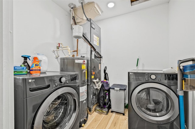 laundry area with washer and clothes dryer, electric water heater, laundry area, and wood finished floors