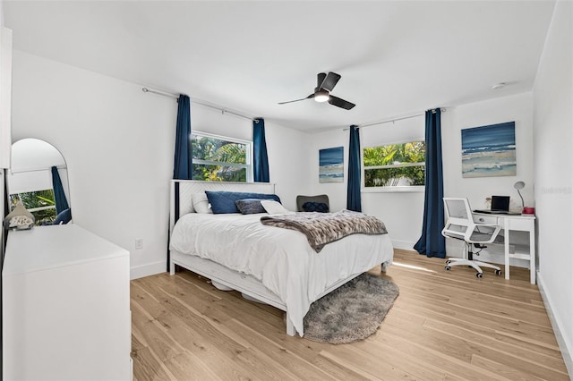 bedroom with light wood-style flooring, baseboards, and a ceiling fan