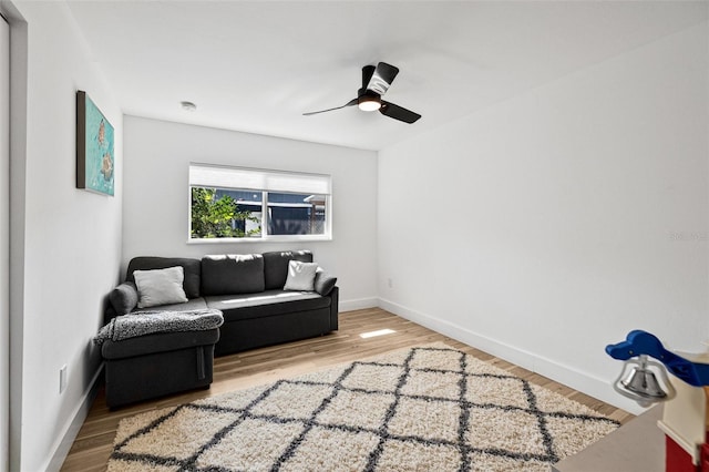 living area with ceiling fan, baseboards, and wood finished floors