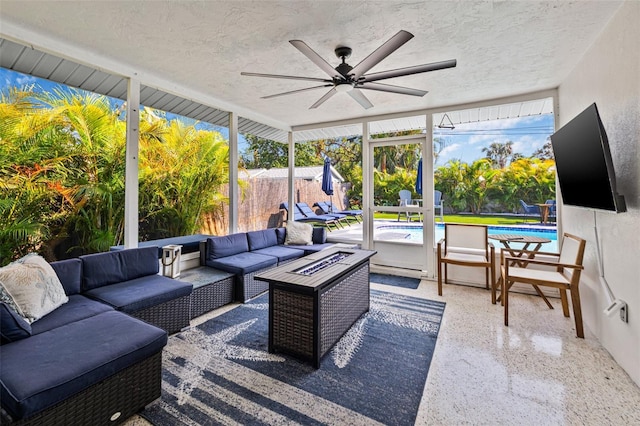 sunroom with a ceiling fan and an outdoor living space with a fire pit