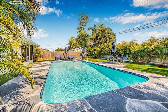 view of swimming pool featuring a yard, a fenced backyard, a fenced in pool, and a patio
