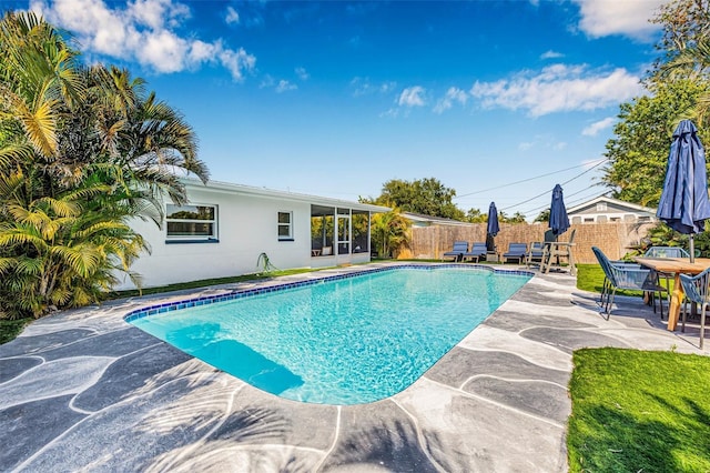 view of swimming pool featuring fence, a fenced in pool, a patio, and a sunroom