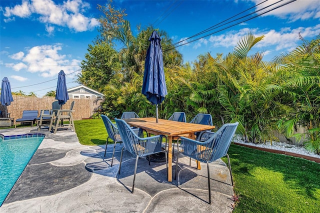 view of patio featuring outdoor dining space, fence, and a fenced in pool