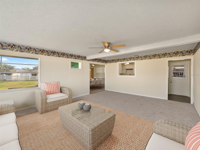 carpeted living room with a textured ceiling, baseboards, and ceiling fan
